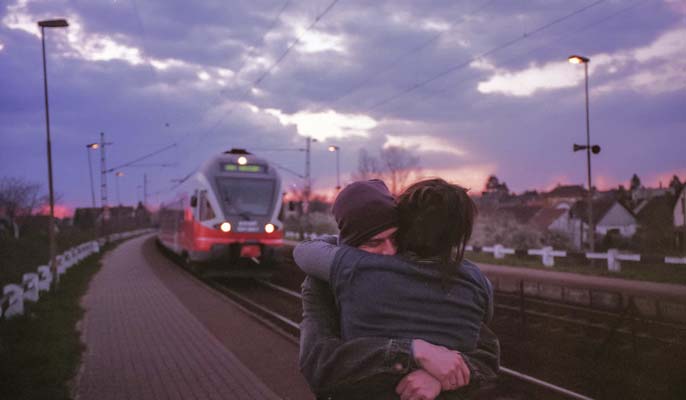 long distance couple hugging goodbye at trainstation