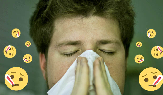 boy sick at uni sneezing into tissue